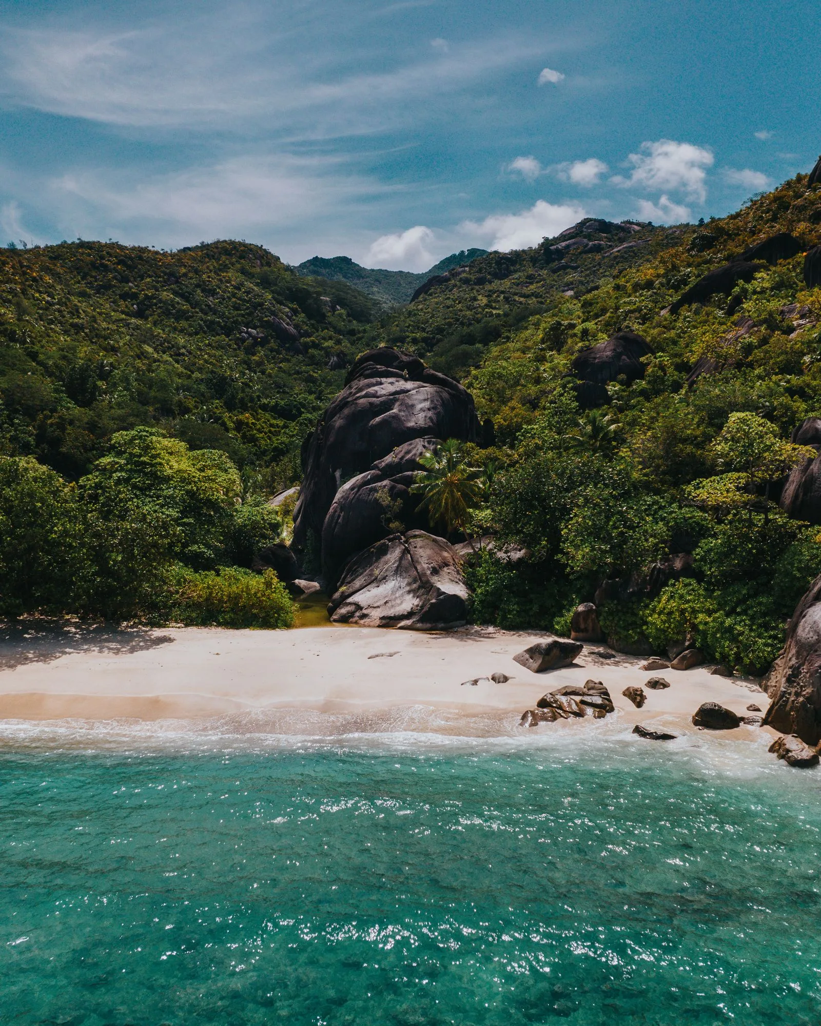 Seychelles beach below forested granite hills